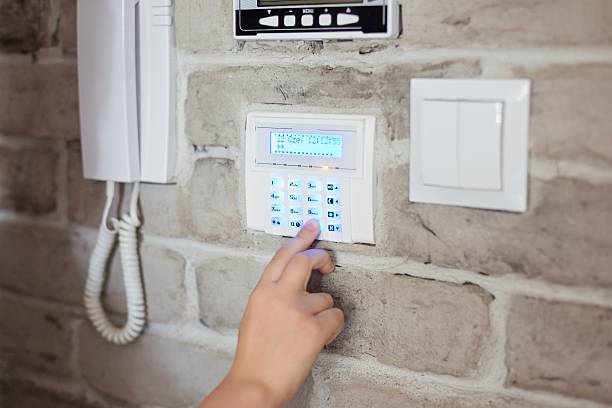 Little baby boy pushes a buttons on the alarm keypad - home security system mounted on wall